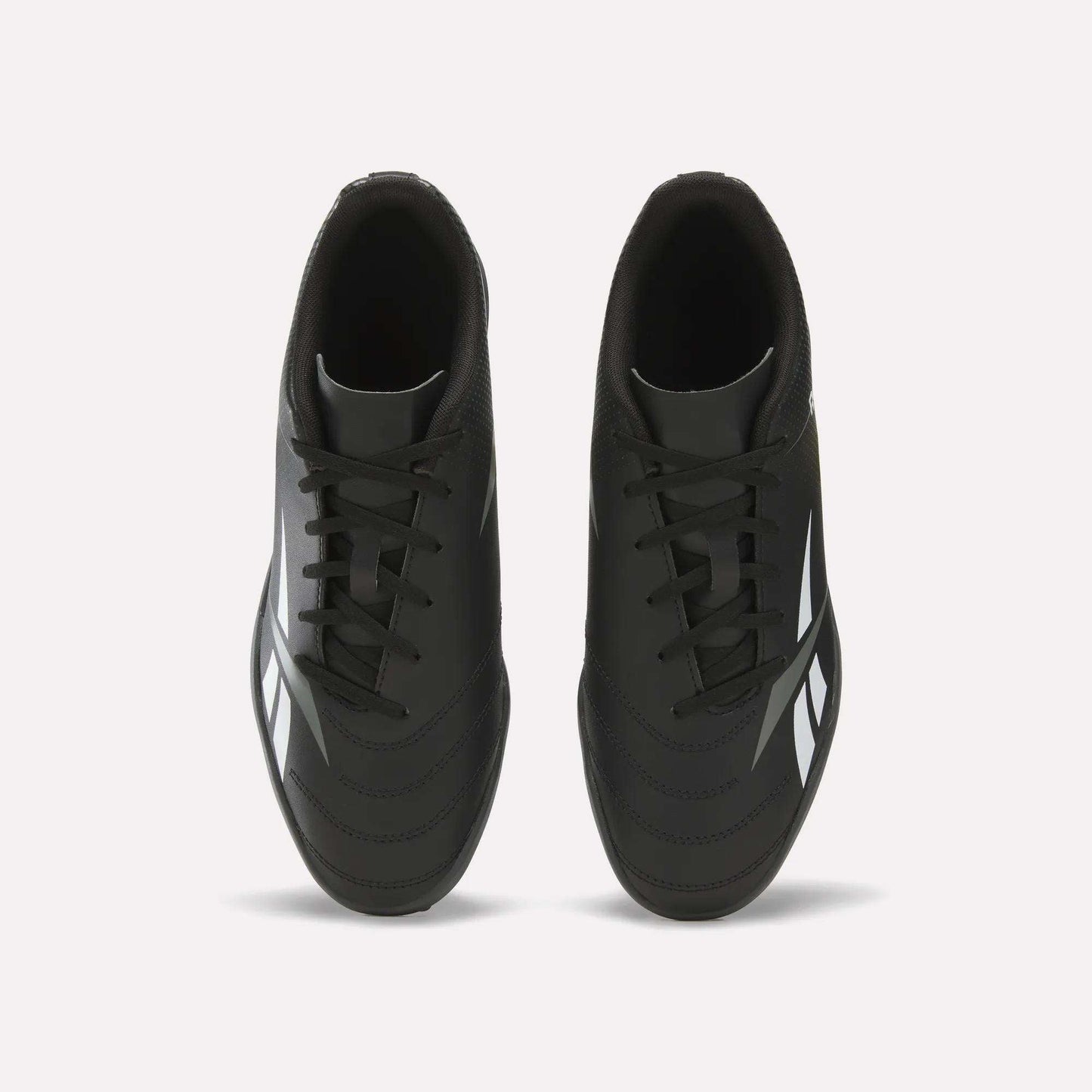 Top view of a pair of Reebok Strike Turf Soccer Shoes in black with white accents and black laces, placed side by side on a plain white background—perfect for soccer practice.