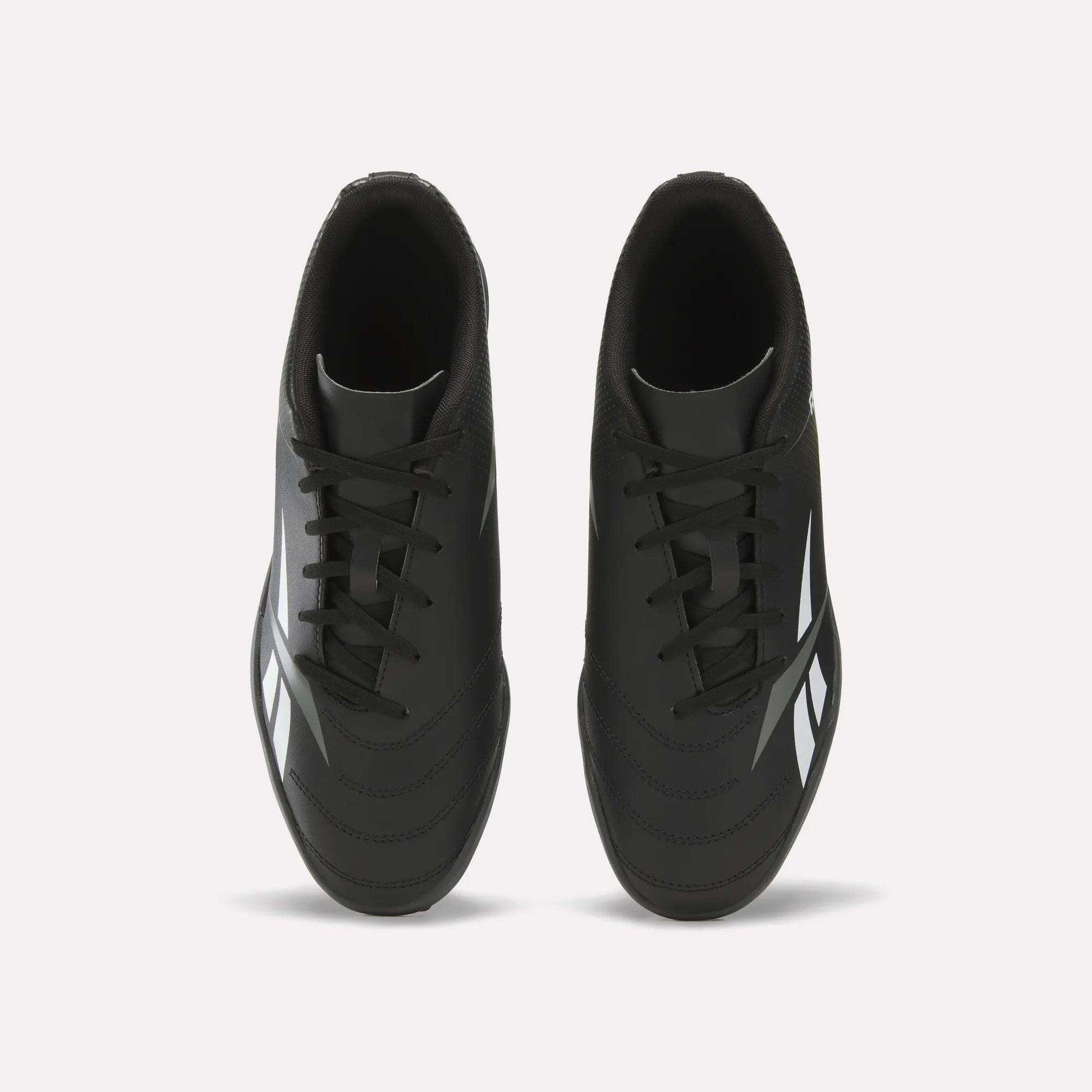 Top view of a pair of Reebok Strike Turf Soccer Shoes in black with white accents and black laces, placed side by side on a plain white background—perfect for soccer practice.