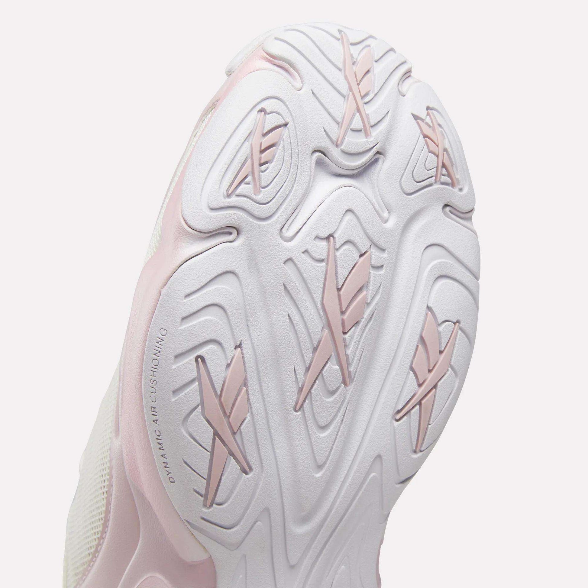 Close-up view of the sole on the Reebok Women's DMX Series 3000 Training Shoes, featuring a textured white design with light pink accents. Inspired by Reebok’s walking shoes, the sole showcases multiple grooves and raised sections for traction, while DMX 3 Technology provides advanced cushioning for superior comfort.