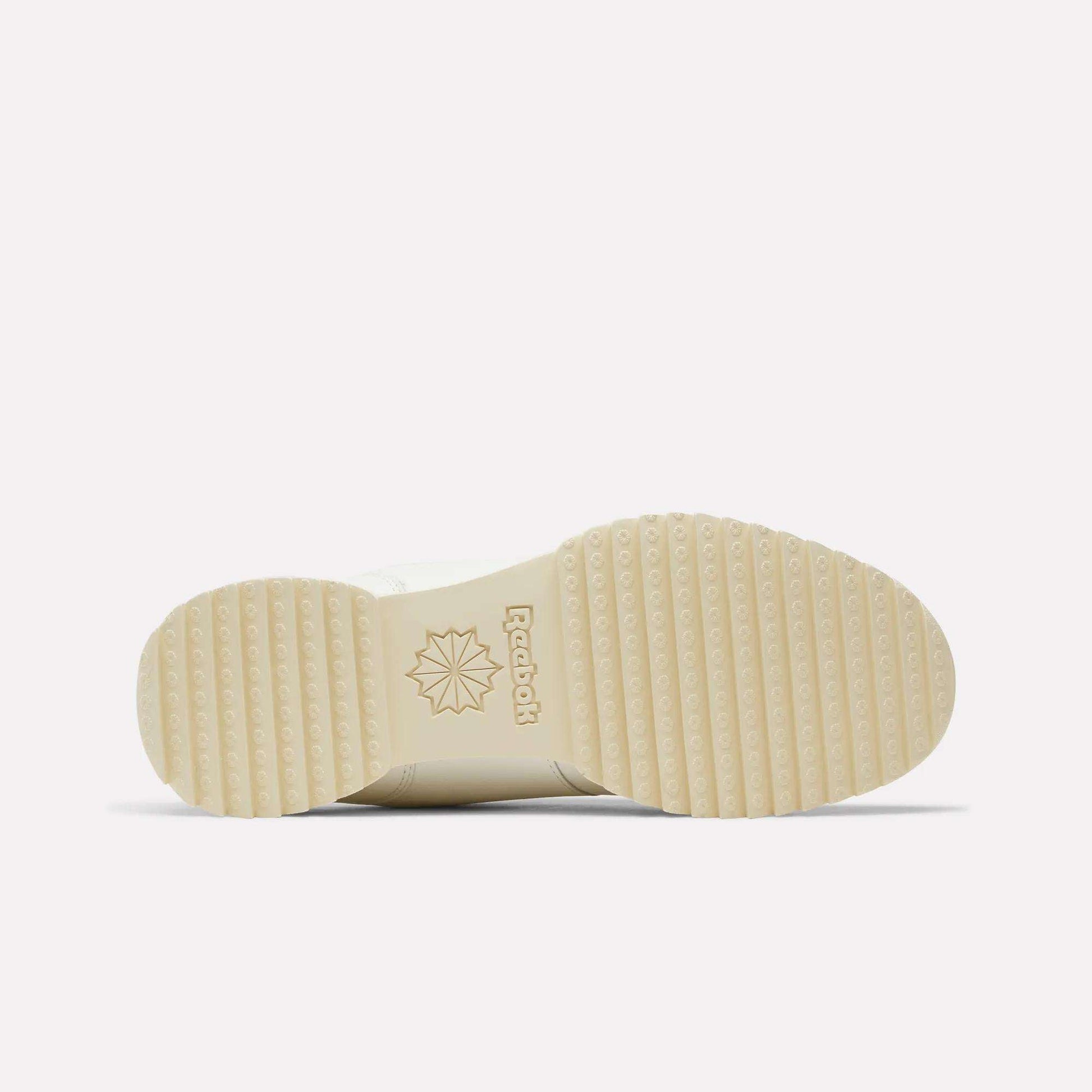 A cream-colored sole of the Reebok Workout Plus Ripple Shoes is shown from the bottom, featuring a ridged tread pattern, the Reebok logo, and a starburst design near the arch—classic details that capture the timeless appeal of vintage leather sneakers.