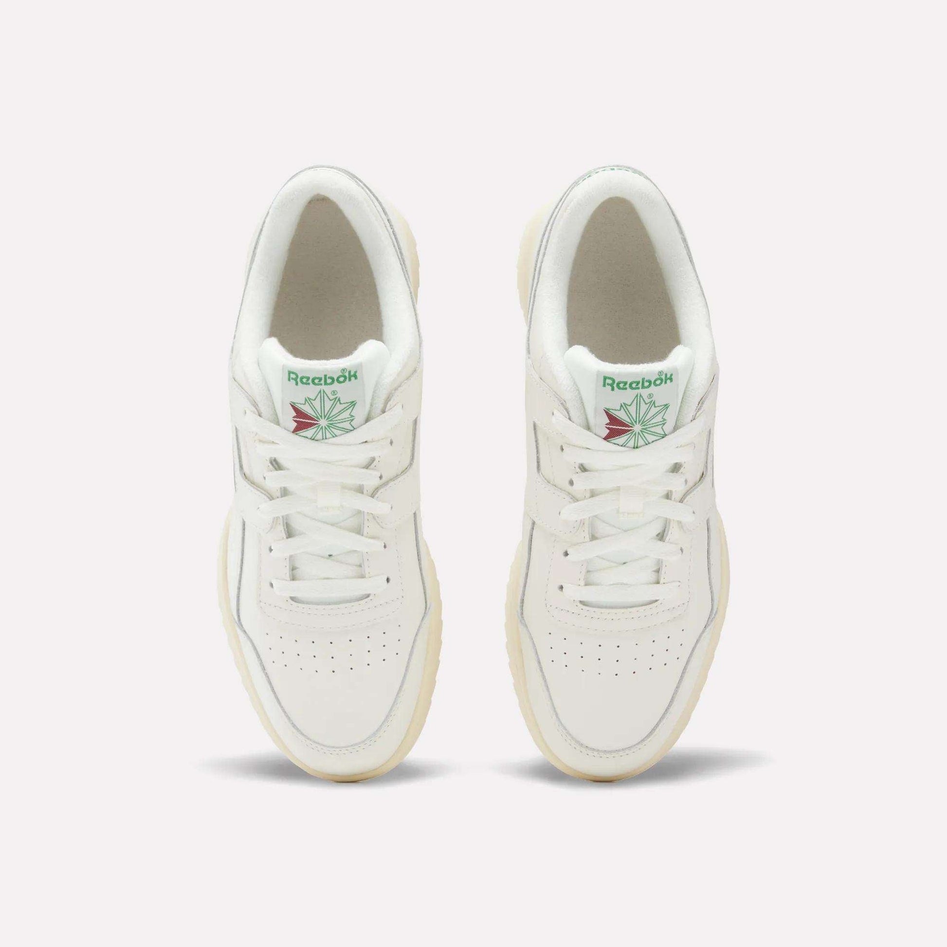 A pair of Reebok Workout Plus Ripple Shoes viewed from above, featuring green Reebok logos with a red and green design on the tongue, white laces, and cream-colored soles.