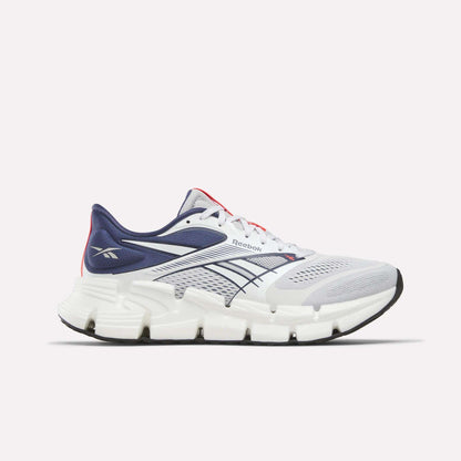 The Reebok Men's FloatZig 2 Running Shoes feature a white and navy mesh upper, Superfloat+ cushioning, thick segmented white sole, navy and black accents, and Reebok logos on the heel and side.