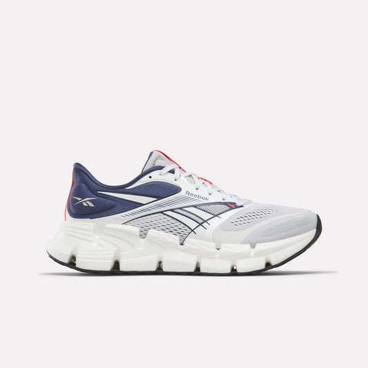 The Reebok Men's FloatZig 2 Running Shoes feature a white and navy mesh upper, Superfloat+ cushioning, thick segmented white sole, navy and black accents, and Reebok logos on the heel and side.