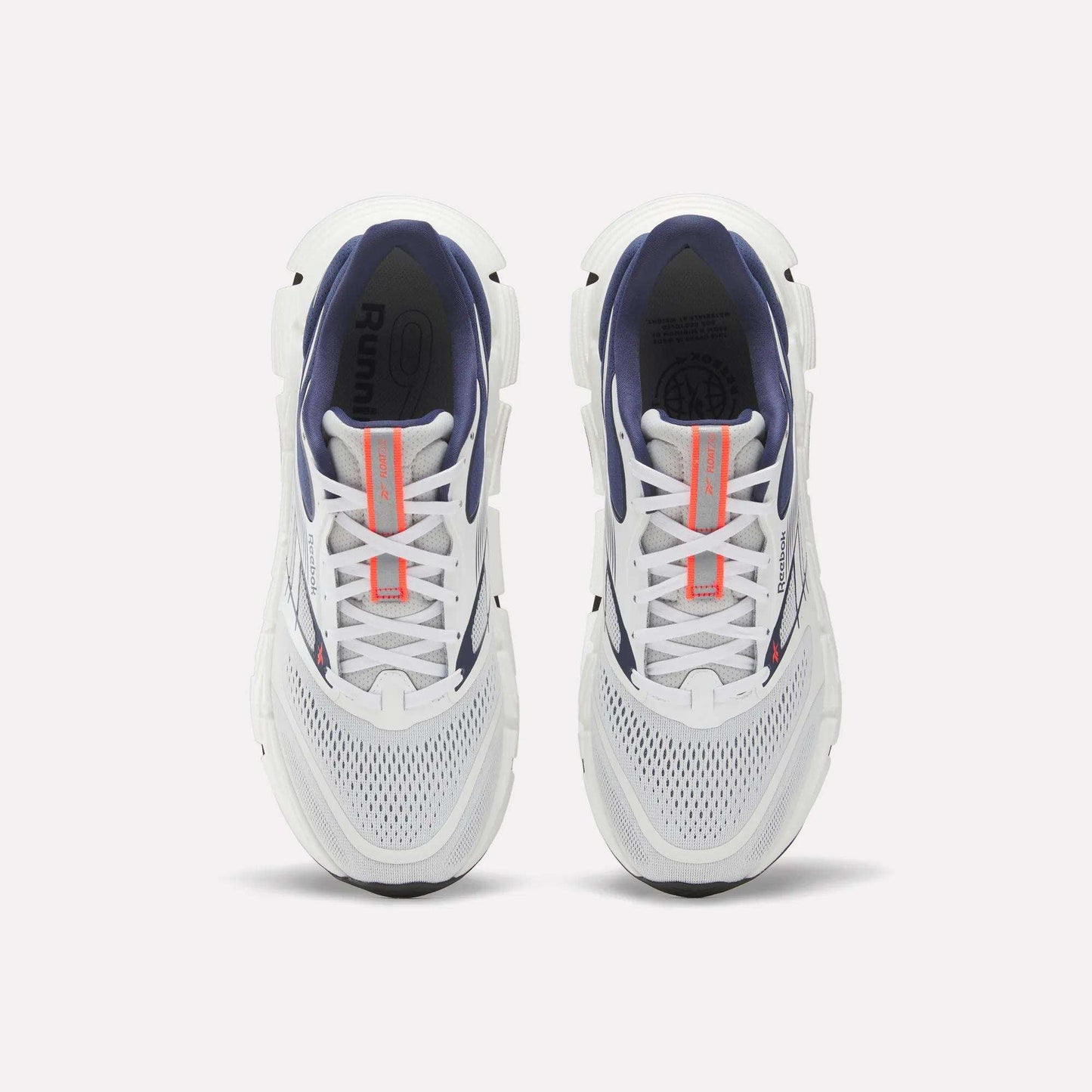 Top view of a pair of Reebok Men's FloatZig 2 Running Shoes with white mesh toes, navy interiors, Superfloat+ cushioning, and orange tongue branding, displayed side by side on a plain white background.