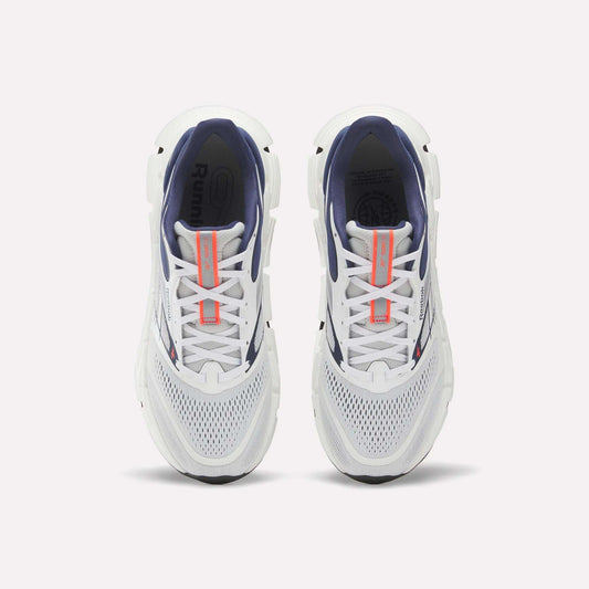 Top view of a pair of Reebok Men's FloatZig 2 Running Shoes with white mesh toes, navy interiors, Superfloat+ cushioning, and orange tongue branding, displayed side by side on a plain white background.
