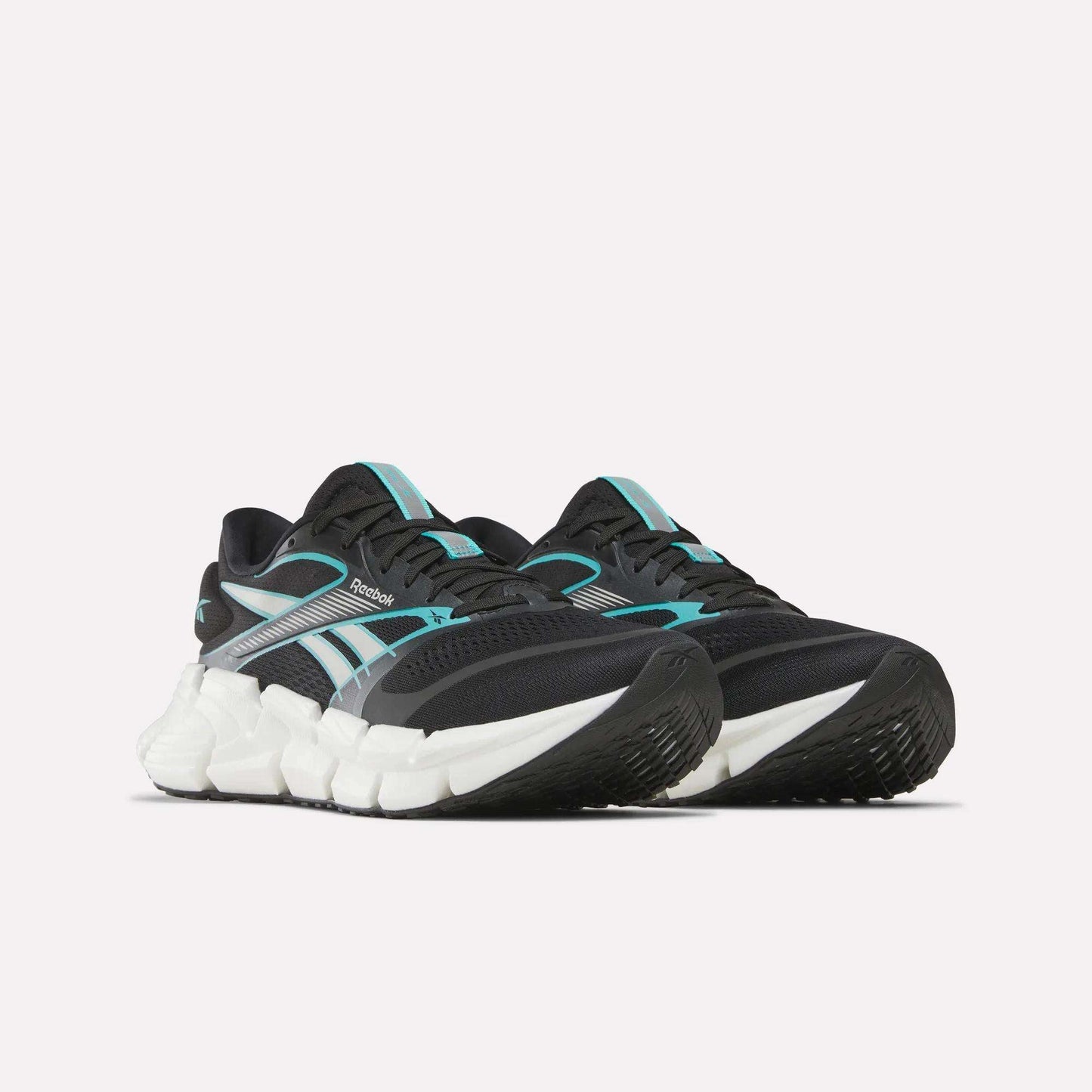 The Reebok Men's FloatZig 2 Running Shoes feature a black upper with teal and white accents, a supportive design, chunky white sole, energy-returning cushioning, and a textured black outsole, shown against a plain white background.
