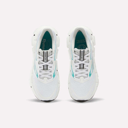 Top view of a pair of white Reebok Women's FloatZig 2 Running Shoes with turquoise accents and black soles on a plain white background. The insoles feature branding and design details, highlighting their springy cushioning.