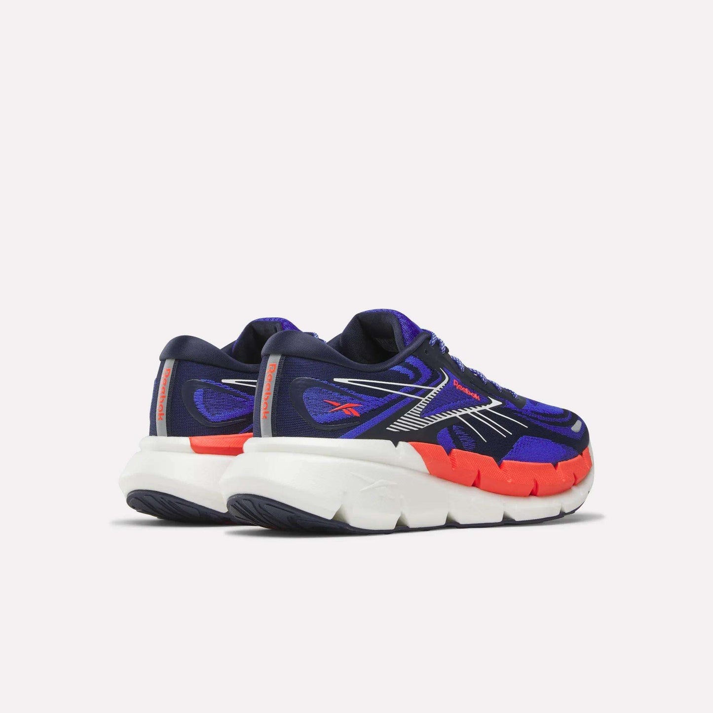 The Reebok Men's FloatZig Double Running Shoes feature navy blue and purple uppers with orange accents, silver detailing, thick white soles, and StableStack construction, shown from the back and side on a light background.