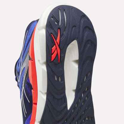 Close-up of the sole on Reebok Men's FloatZig Double Running Shoes, featuring a blue, white, and red color scheme. The outsole has textured grooves and a red Reebok logo on the heel for max-cushioned running comfort.