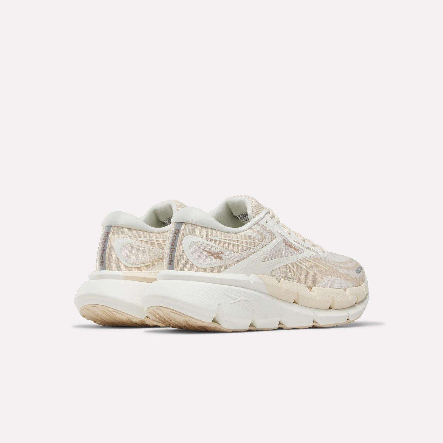 A pair of Women's FloatZig Double Running Shoes by Reebok in chunky off-white with beige accents and thick, textured soles—perfect for max-cushioned miles—viewed from the back left side against a plain light background.
