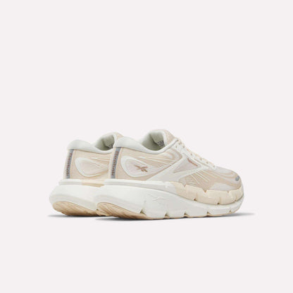A pair of Women's FloatZig Double Running Shoes by Reebok in chunky off-white with beige accents and thick, textured soles—perfect for max-cushioned miles—viewed from the back left side against a plain light background.