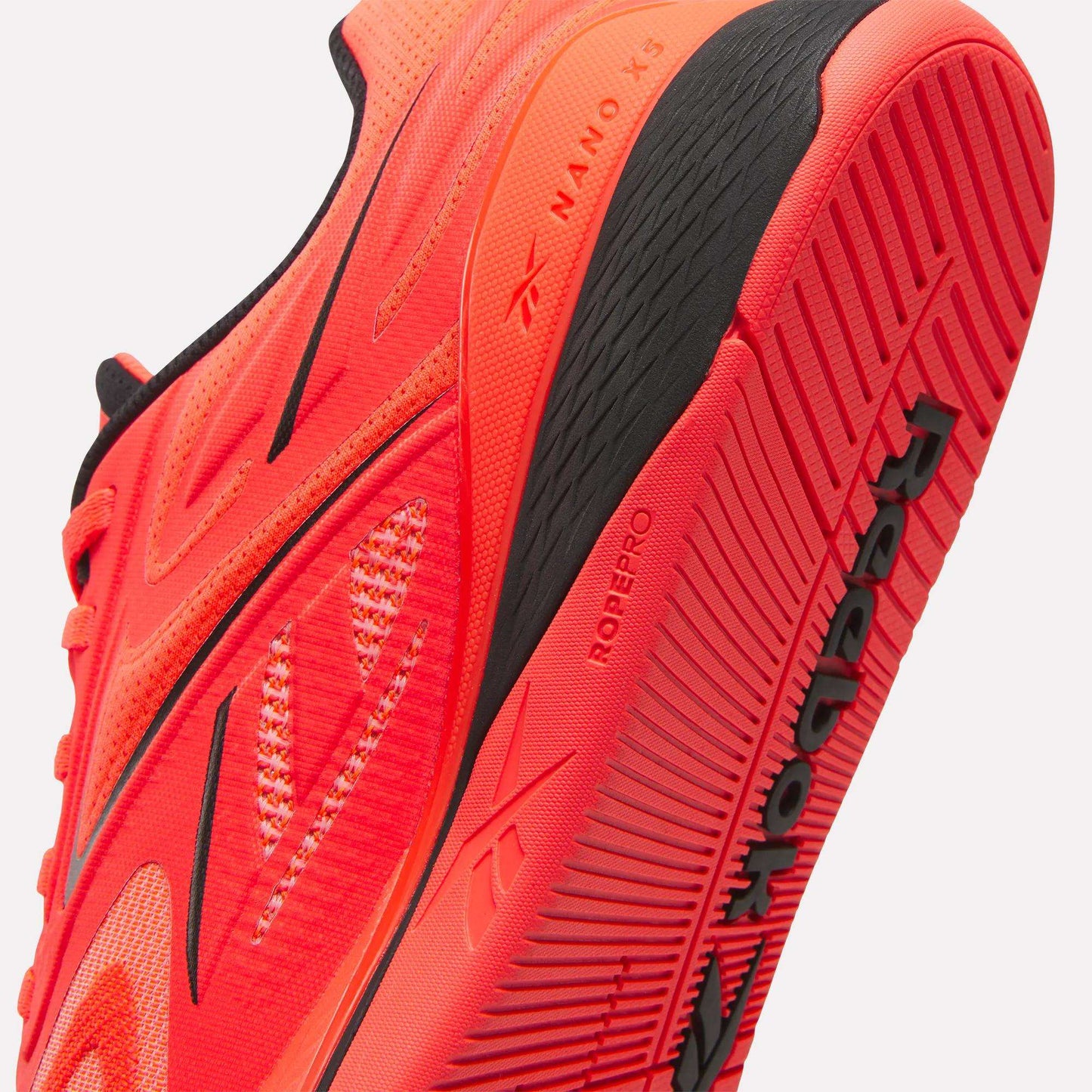 Close-up of a vivid red Reebok Nano X5 Edge Training Shoe with black accents, focusing on the sole and side details to showcase the advanced performance features of this Reebok model.