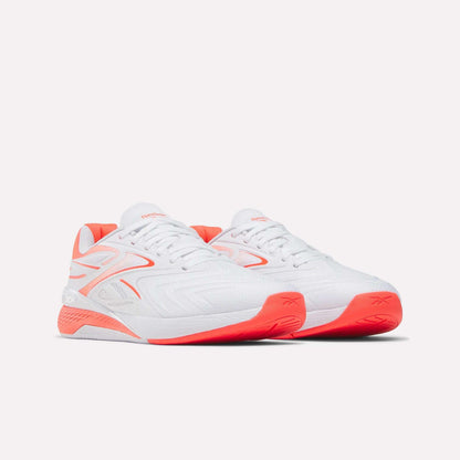 A pair of Reebok Women's Nano X5 Edge Training Shoes in white with bright coral accents and soles are displayed on a plain light background, facing slightly right.