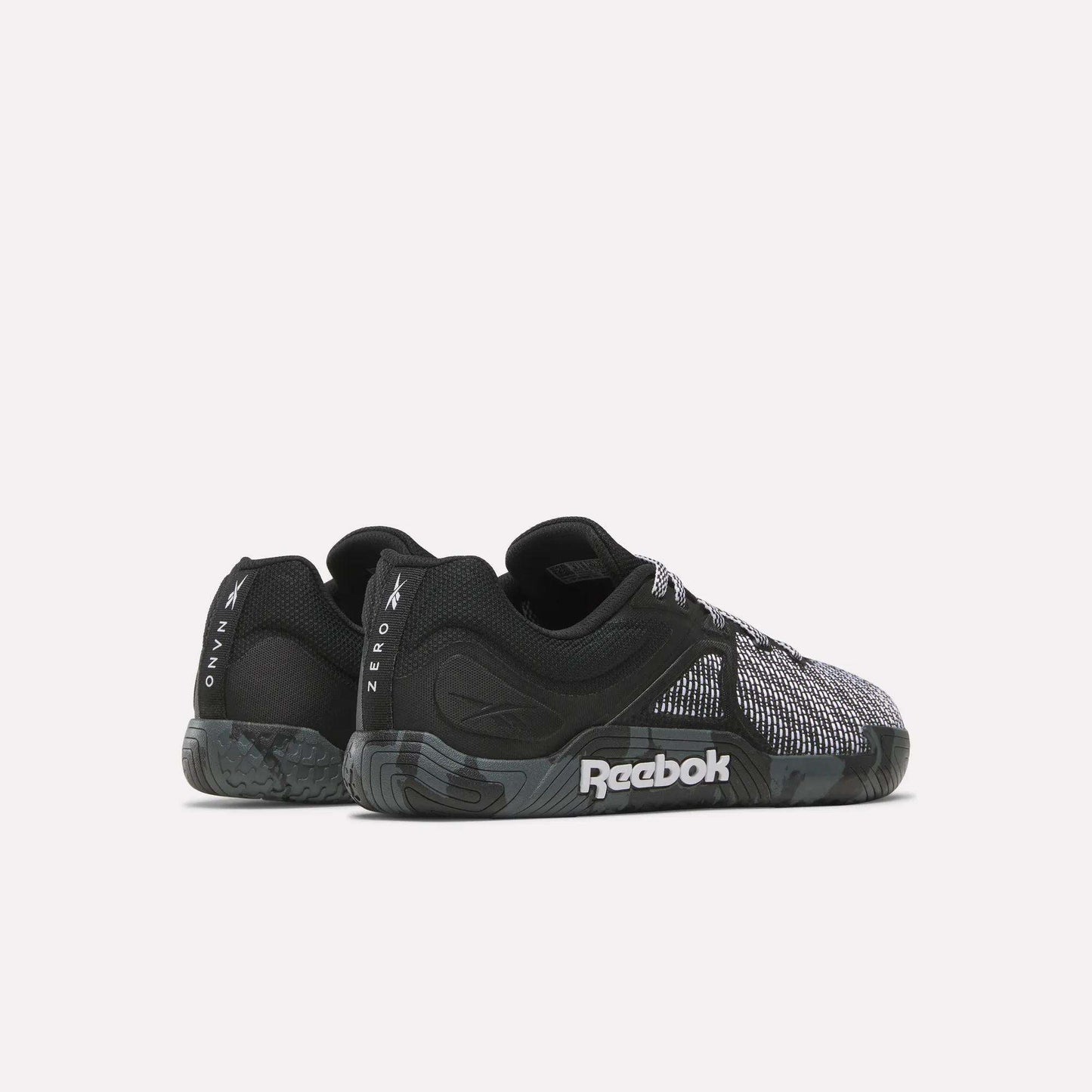 A pair of black and gray Reebok Nano Zero Training Shoes with textured soles and mesh details, ideal for strength training. Viewed from the side and slightly angled to the back. The Reebok logo is visible on the sole and heel.