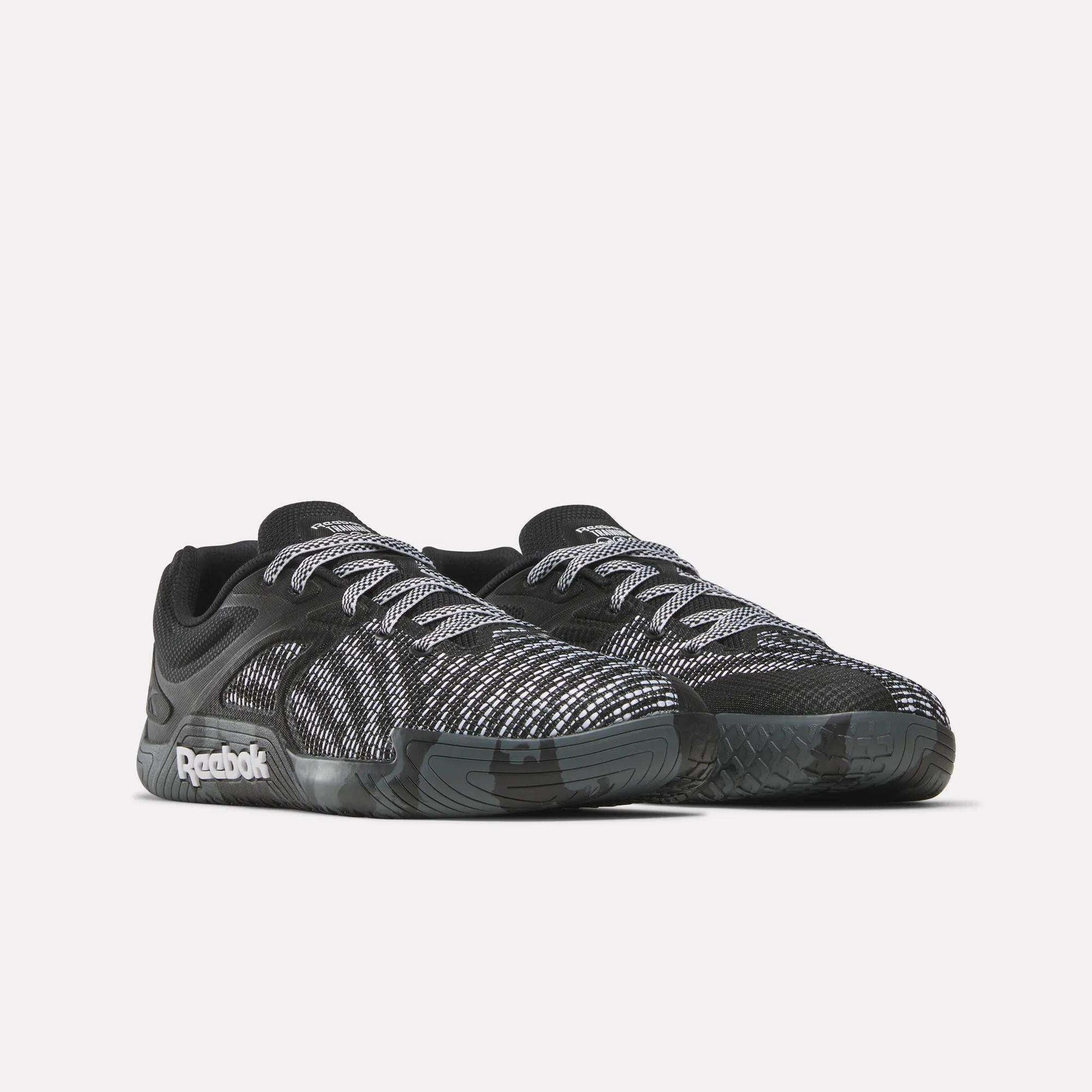 The Reebok Nano Zero Training Shoes feature black uppers with white and gray patterns, white laces, and a black sole—ideal for strength training. Shown on a plain white background.