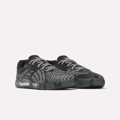 The Reebok Nano Zero Training Shoes feature black uppers with white and gray patterns, white laces, and a black sole—ideal for strength training. Shown on a plain white background.
