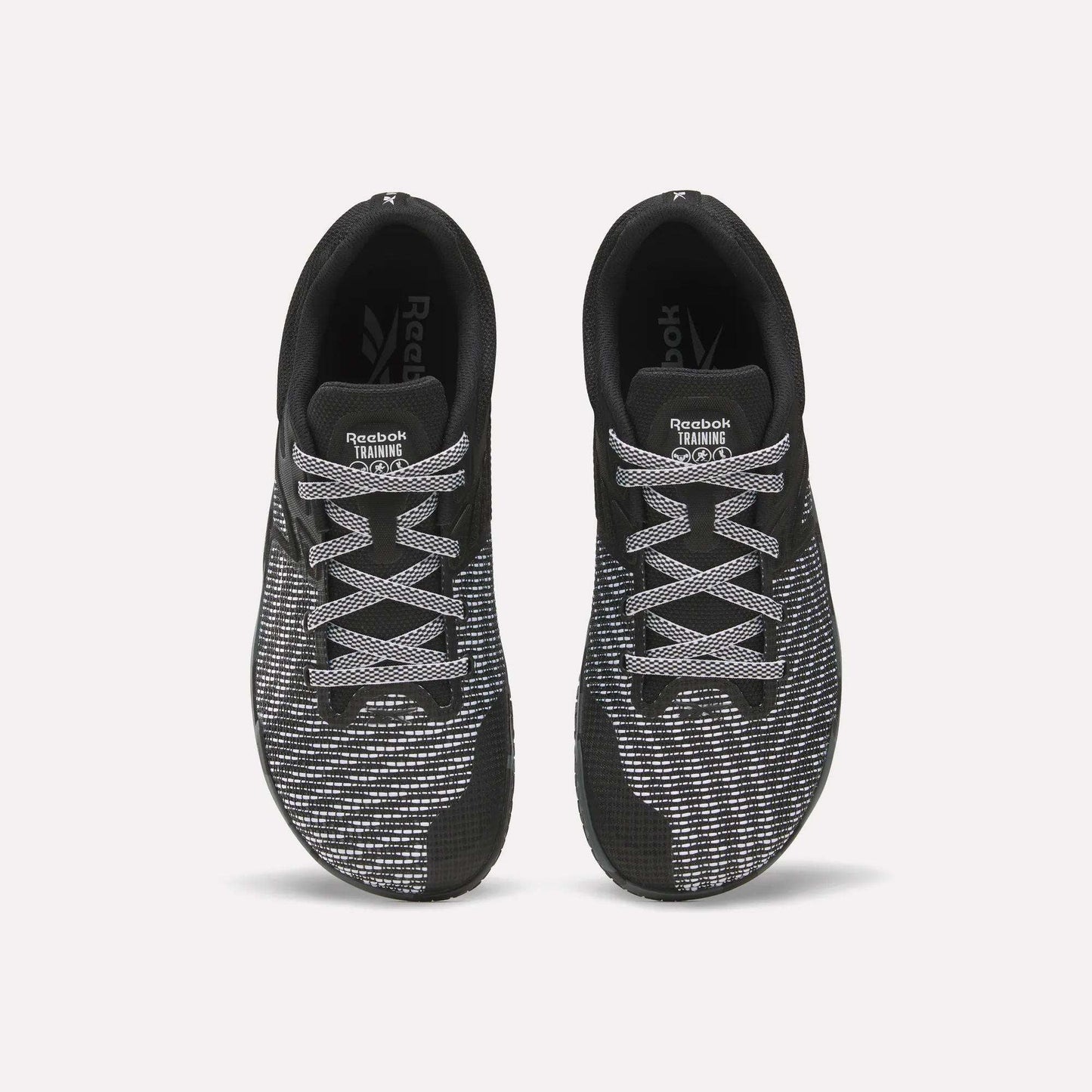 Top view of a pair of Reebok Nano Zero Training Shoes in black with white and gray patterned laces and mesh uppers, ideal for strength training, displayed side by side on a plain white background.