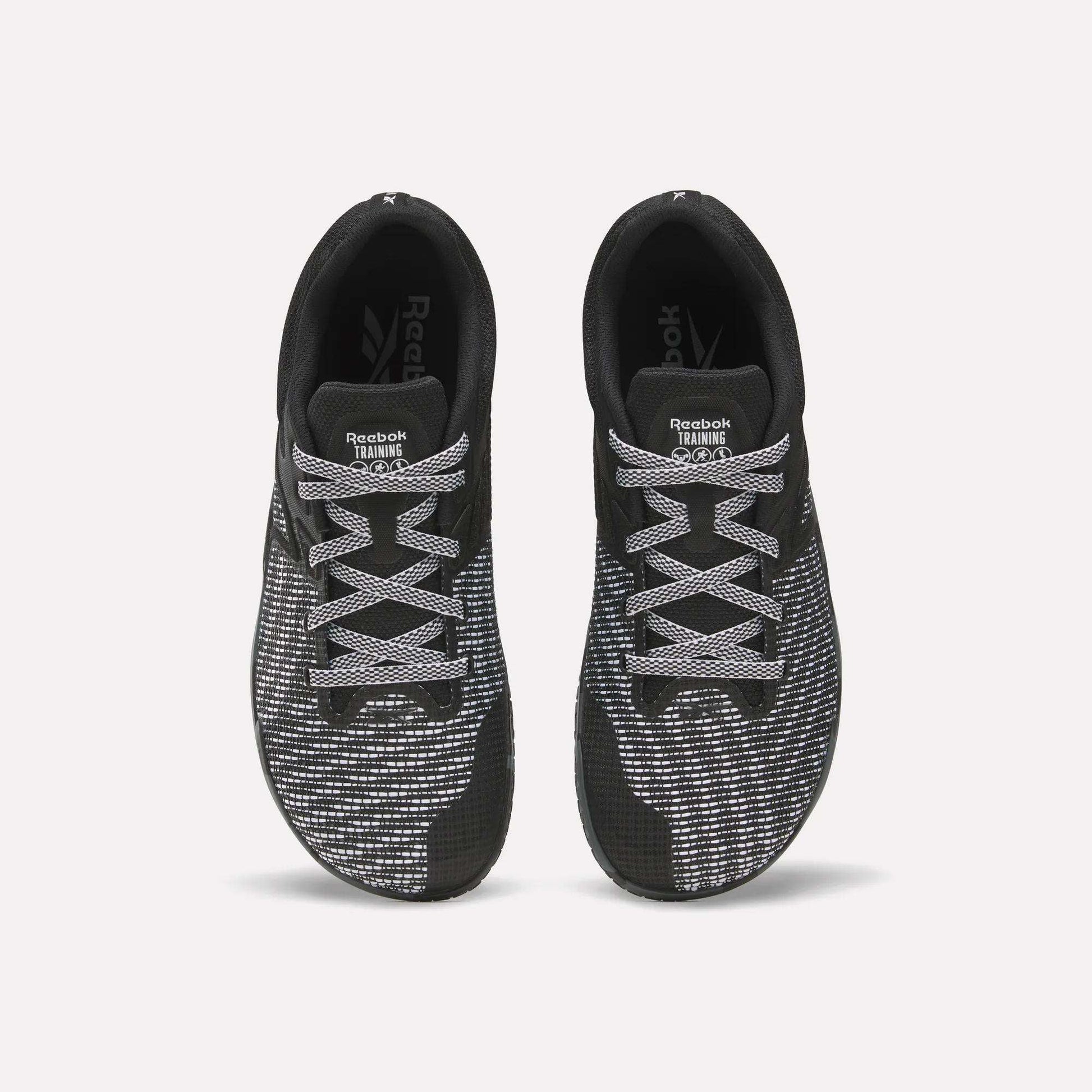 Top view of a pair of Reebok Nano Zero Training Shoes in black with white and gray patterned laces and mesh uppers, ideal for strength training, displayed side by side on a plain white background.