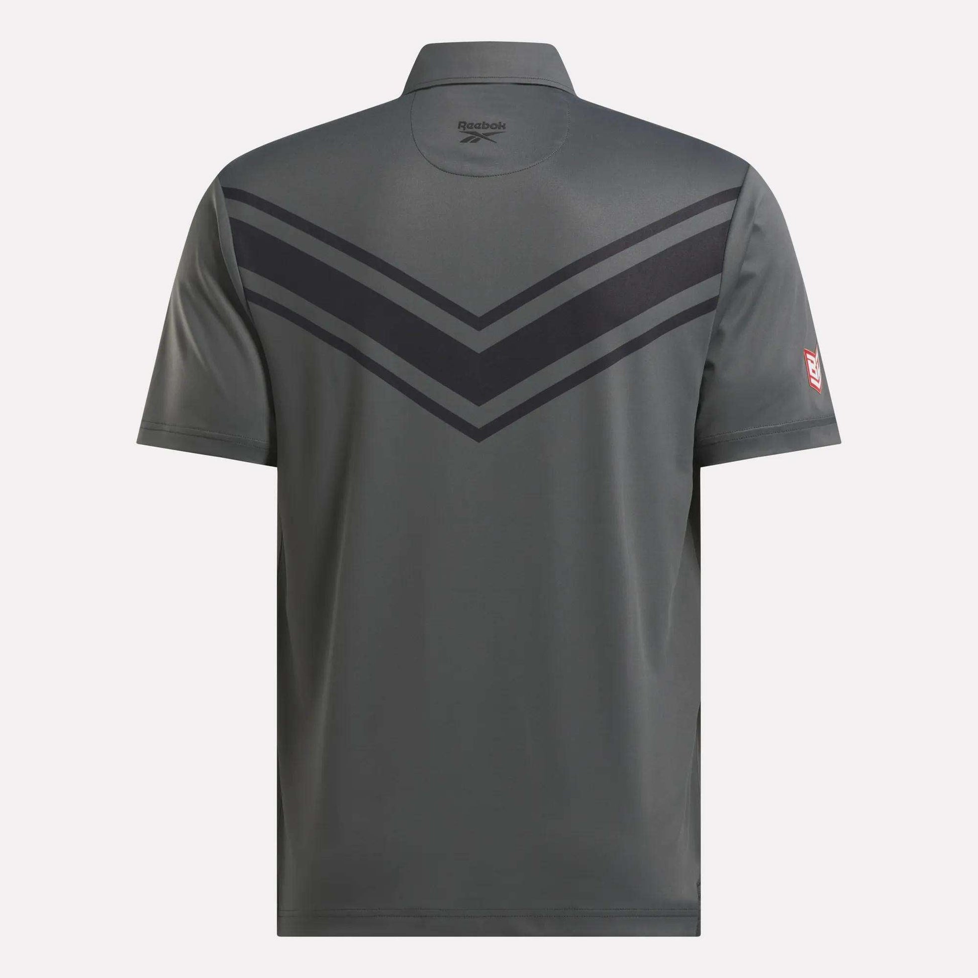 A gray Reebok Men's BDC Colorblocked Polo Shirt seen from the back features RBK-DRY tech, two dark chevron stripes on the upper back, the Reebok logo below the collar, and a small red patch on the left sleeve.