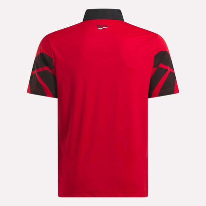Back view of the Reebok Men's Signature Vector Colorblocked Polo Shirt in red, featuring short sleeves, a black collar, black geometric sleeve patterns, moisture-wicking fabric, and UPF 30+ protection.