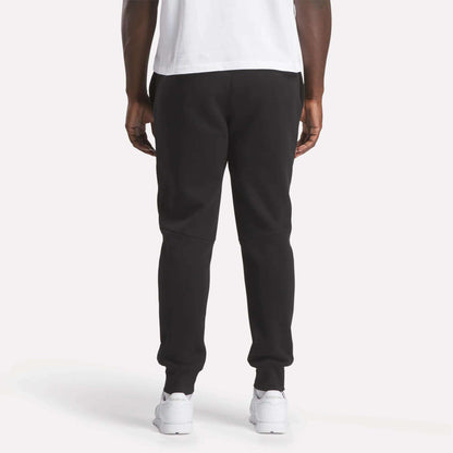 A man wearing Reebok Men's Motion Joggers in black and a white shirt.