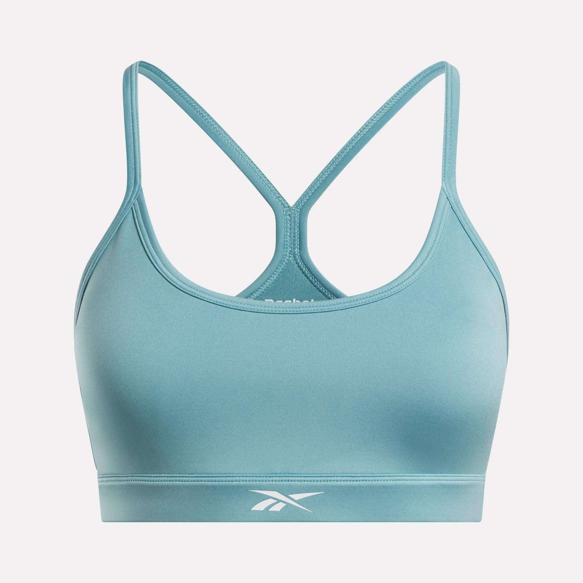 The Women's Strappy Sports Bra by Reebok features a light blue hue, thin shoulder straps, a racerback design, and a white Reebok logo on the bottom band. Designed for medium-impact workouts, this bra is showcased against a plain white background.