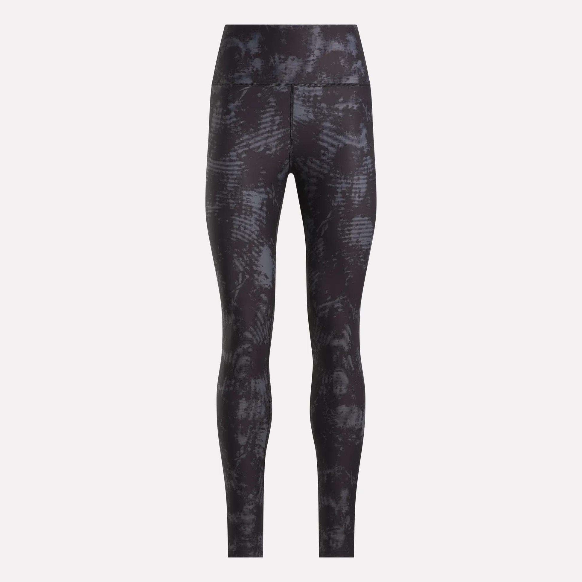 Reebok Women's High-Rise Printed Leggings showcase an abstract dark gray and black design, made from sweat-wicking fabric, shown against a plain light background.