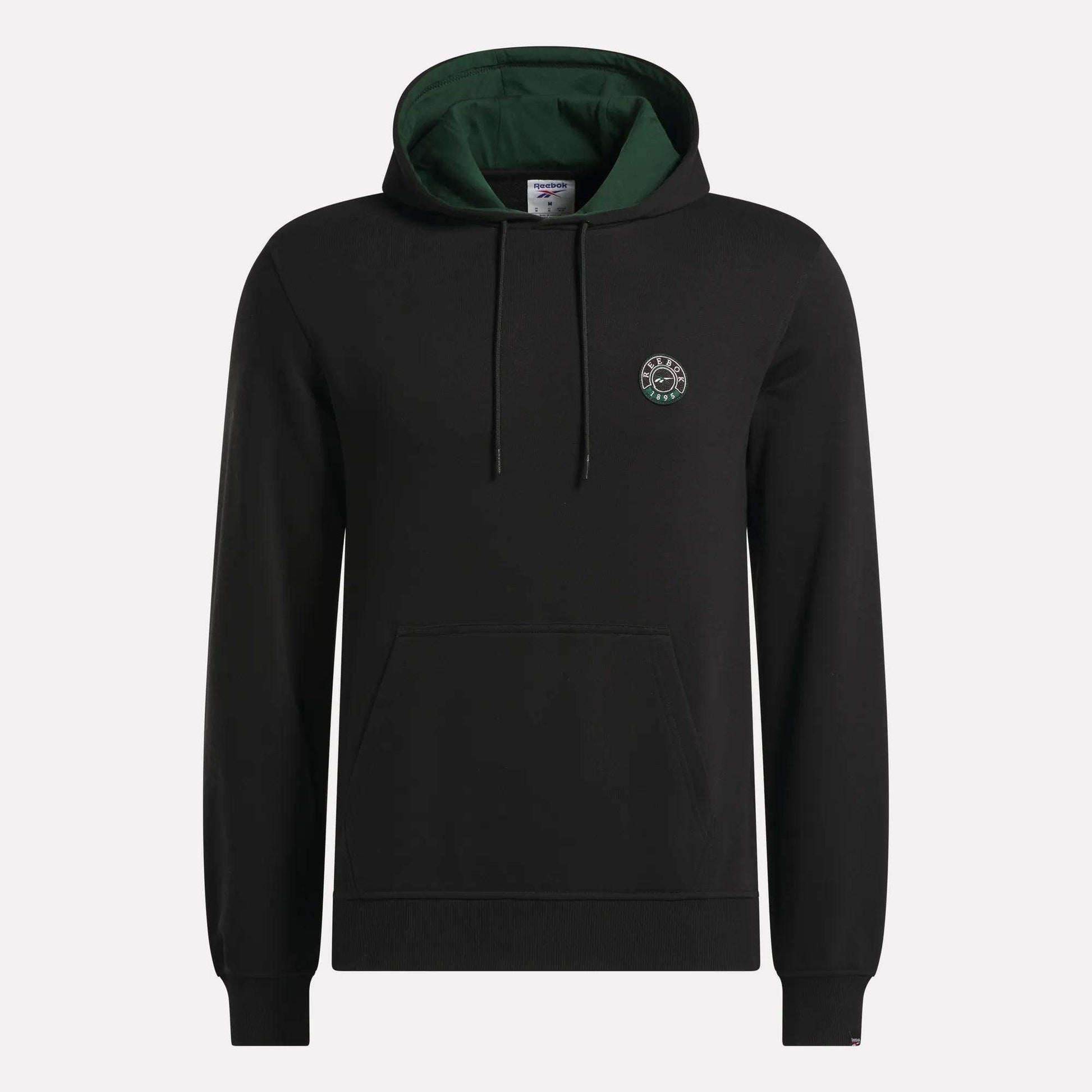 The Reebok Men's French Terry Hoodie is crafted from comfortable French terry fabric and features a black design with a green-lined hood, adjustable drawstrings, a convenient front pocket, and a small circular logo on the left chest. The hoodie is shown against a plain light background.