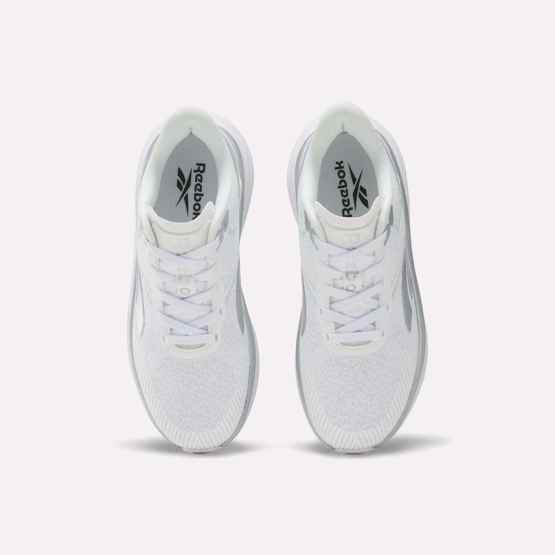 Top view of a pair of white Women's Viva Speed Shoes by Reebok with laces, featuring a cushioned midsole for added comfort, placed side by side on a plain white background.