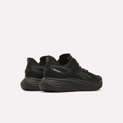 The Reebok Men's Viva Speed Shoes, shown from a rear side angle on a white background, feature black mesh uppers and thick wavy soles, delivering a perfect mix of breathability and cushioned comfort.