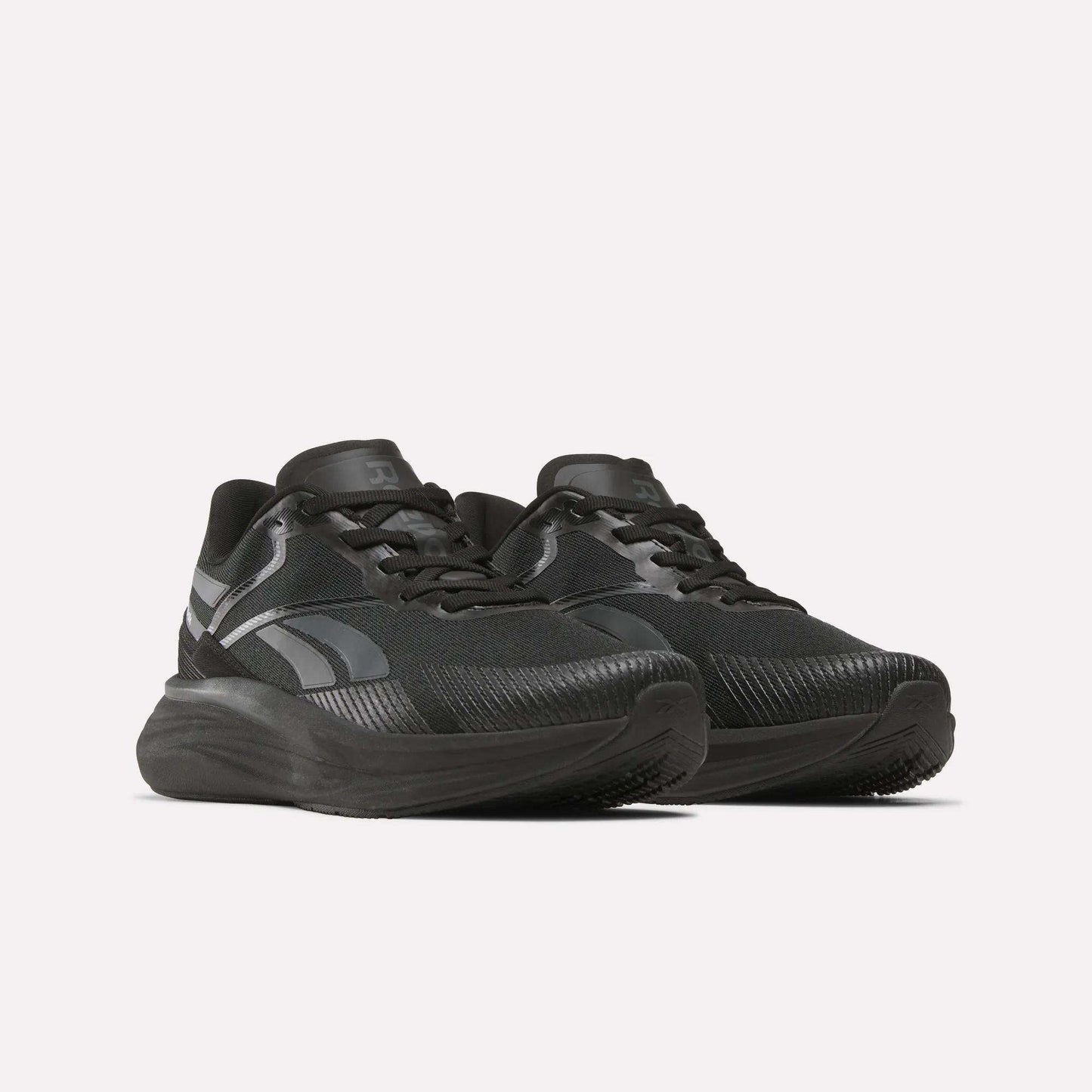 A pair of Men's Viva Speed Shoes by Reebok in black with dark gray accents, thick soles, textured uppers, and black laces are displayed side by side on a white background.