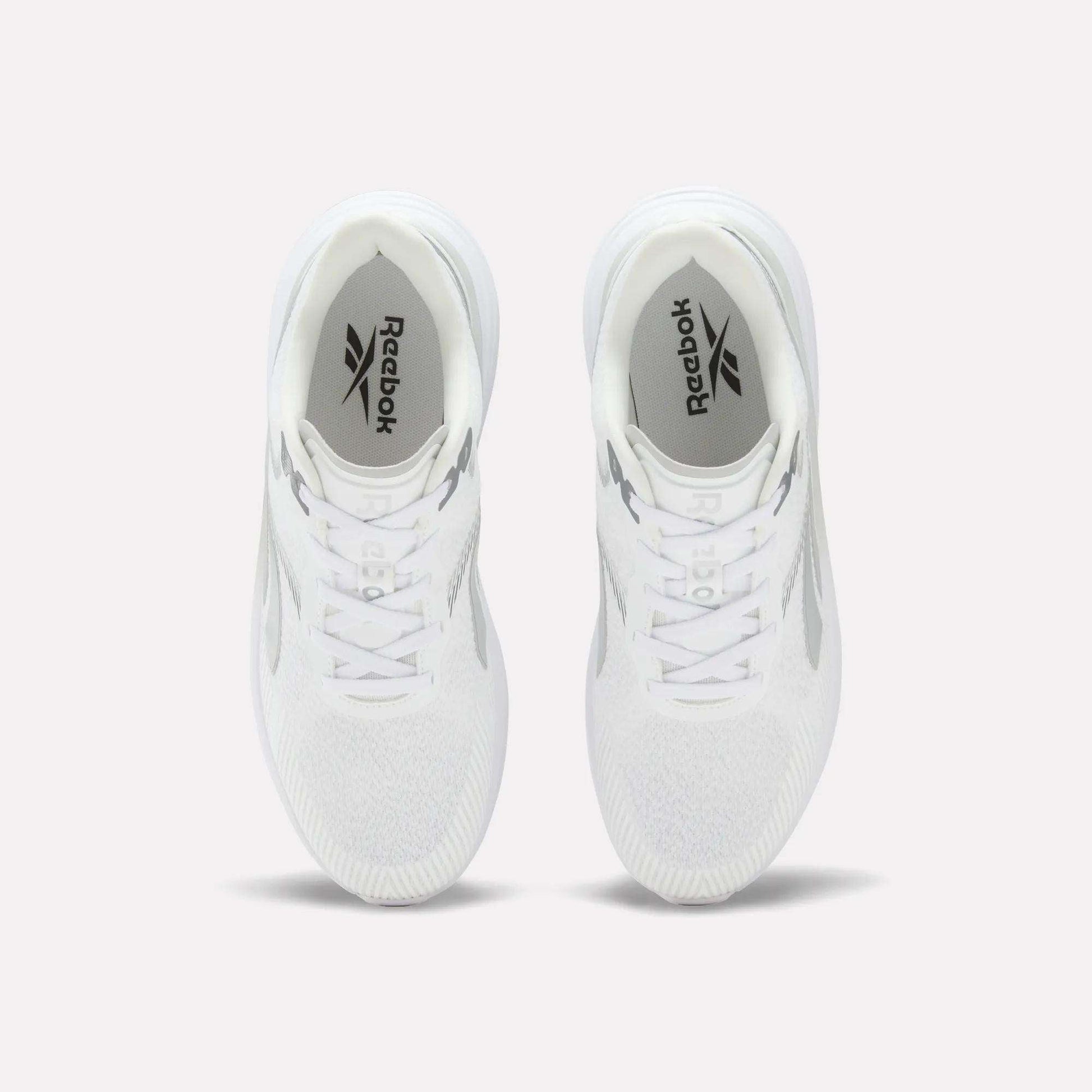 A pair of Men’s Viva Speed Shoes by Reebok in white is displayed from above on a light background, highlighting the Reebok logo on the insoles and the mesh uppers for enhanced breathability.