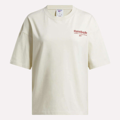 The Reebok Women's League Club Graphic T-Shirt is an off-white cotton tee with a relaxed fit, featuring the red Reebok logo and text on the left chest.