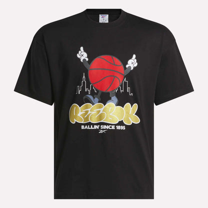 Reebok Men's Basketball T-Shirt—black cotton tee with a cartoon character holding a red basketball, city skyline background, and bold "Reebok Ballin Since 1895" text. Perfect for basketball fans.