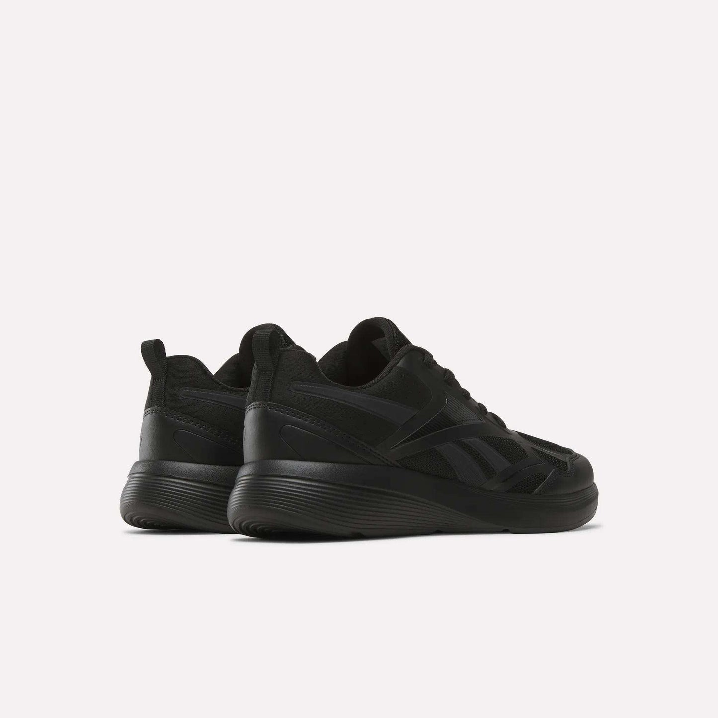 The Rush Runner 6.0 Running Shoes for big kids by Reebok are shown in black, featuring thick EVA midsoles, set against a white background and angled to display both the back and side views.