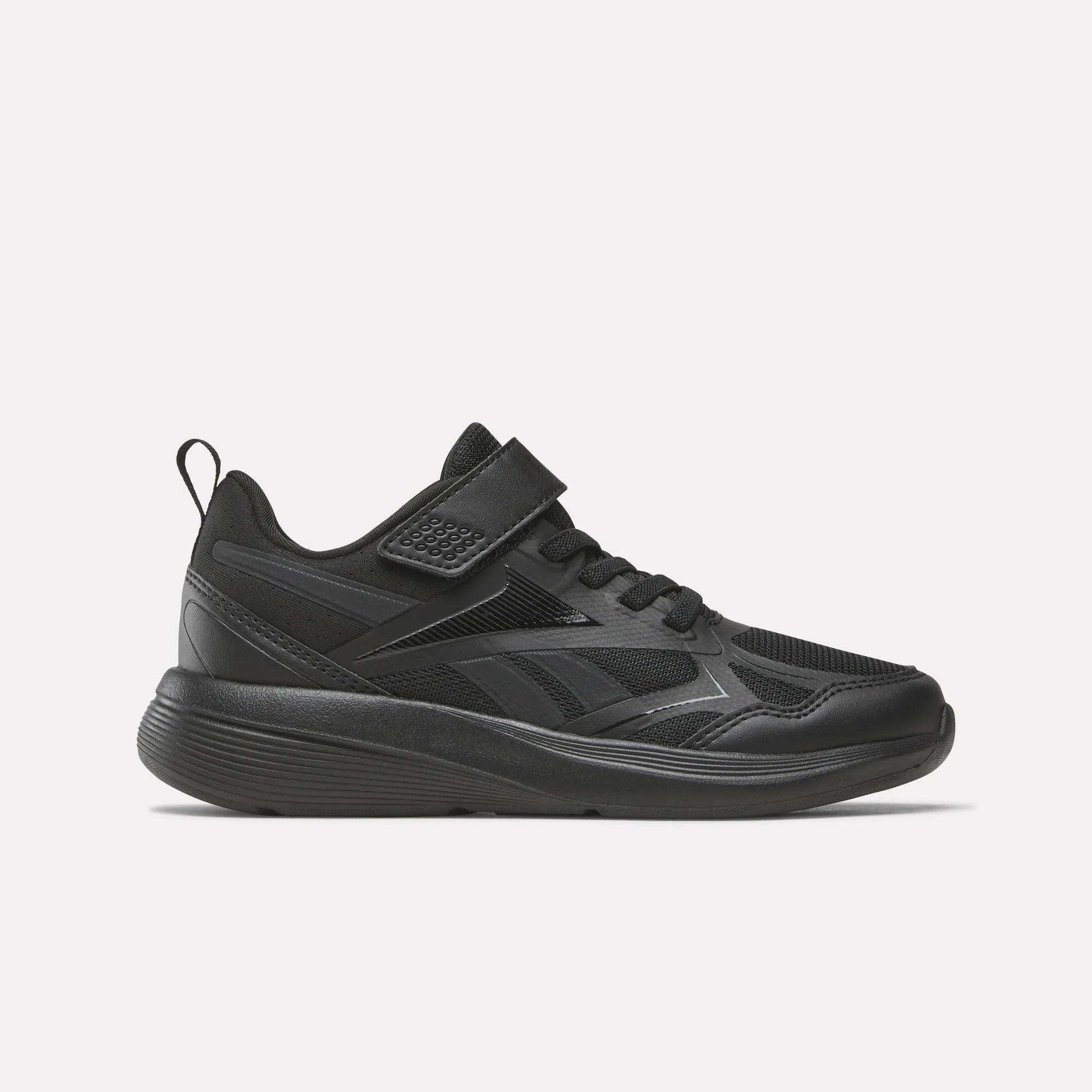 The Reebok Rush Runner 6.0 Elastic Lace Top Strap Running Shoes for little kids in Black/Black/Black feature a mesh and synthetic upper, hook-and-loop strap, and textured rubber sole for all-day comfort, shown in side profile on a white background.