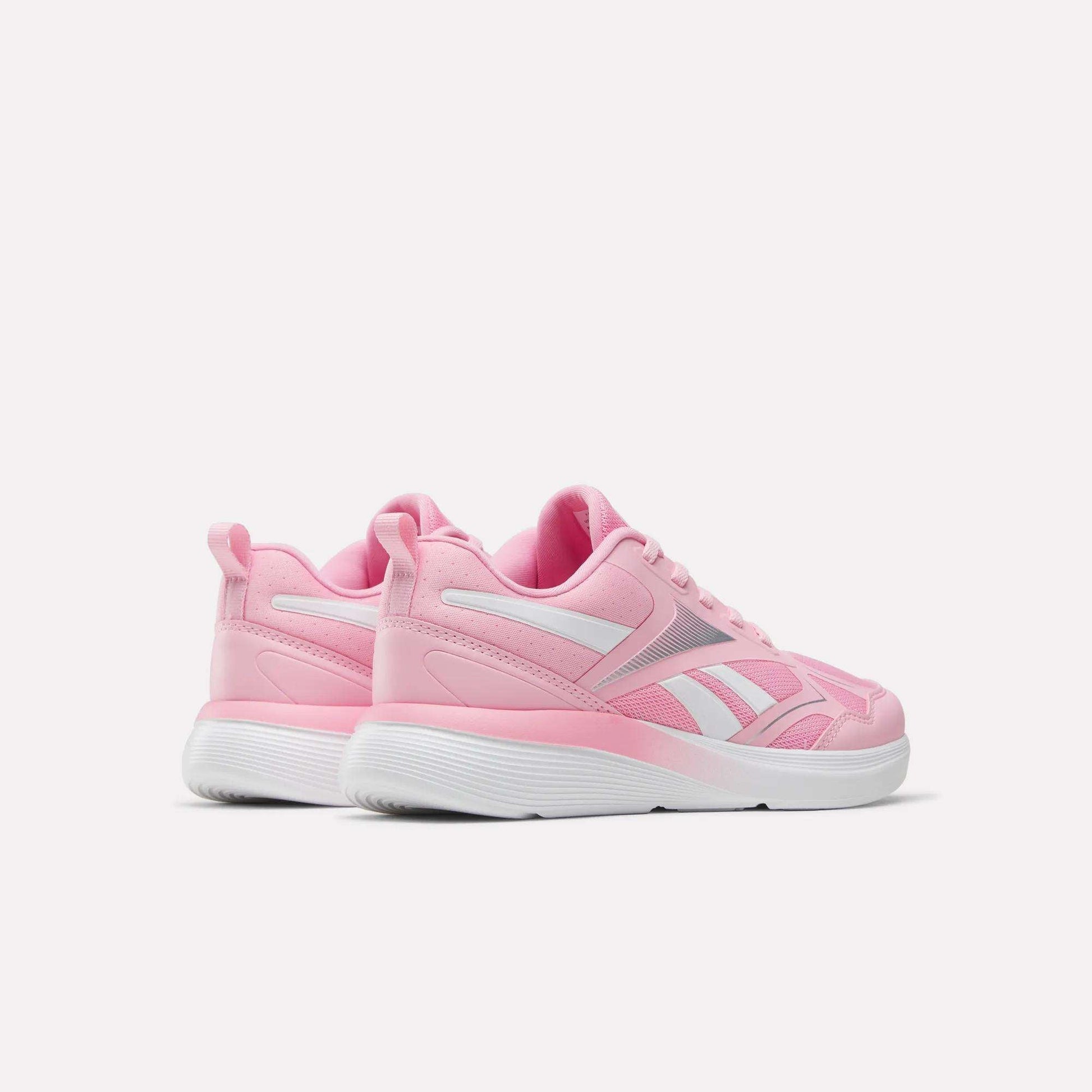 A pair of Reebok Rush Runner 6.0 Running Shoes for big kids in pink and white with white EVA midsoles, shown from the back and side on a plain white background.