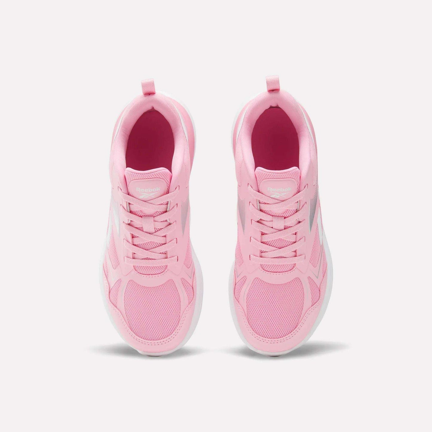 Top view of a pair of light pink Reebok Rush Runner 6.0 Running Shoes for big kids, featuring white EVA midsoles and laces, arranged side by side on a plain white background.