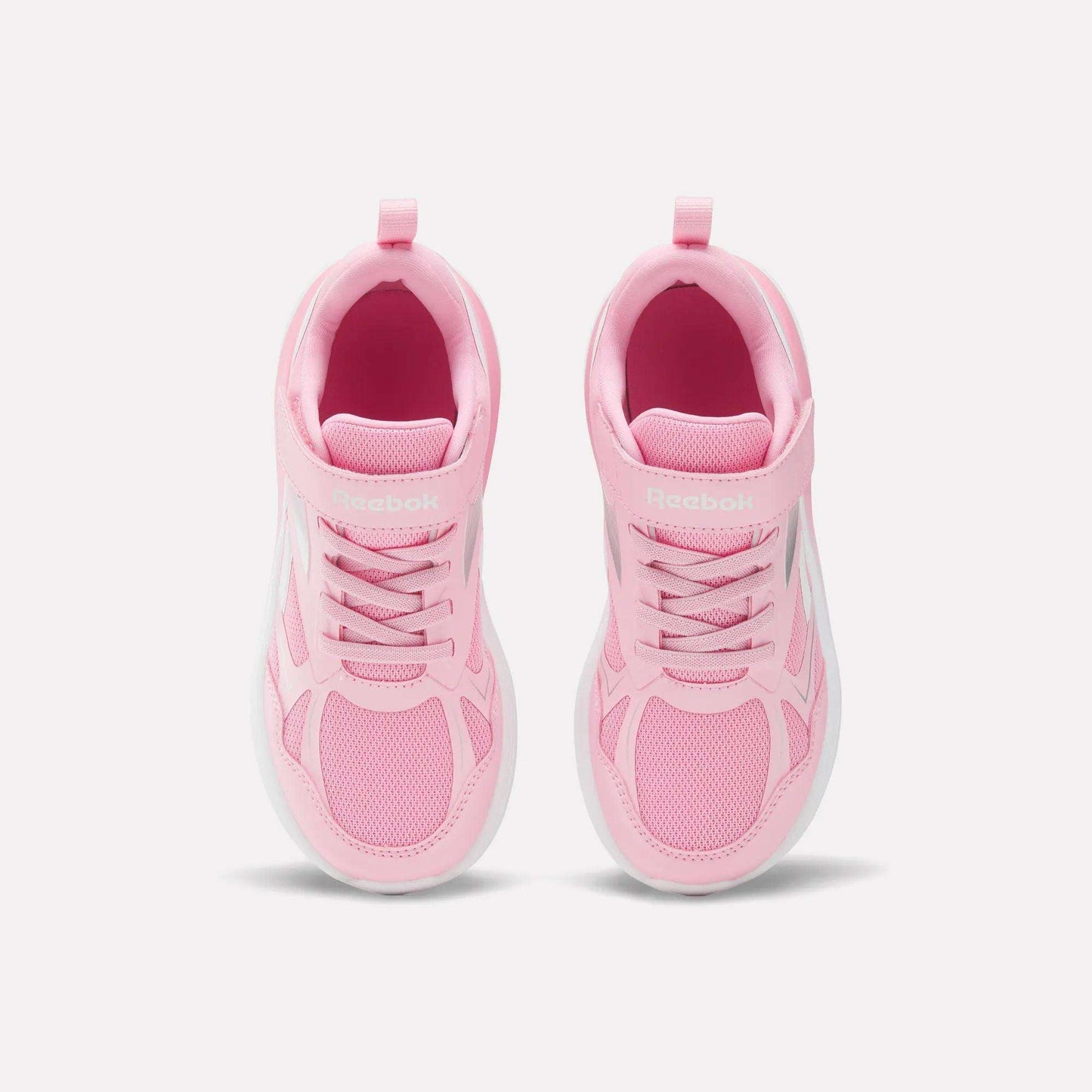 The Reebok Rush Runner 6.0 Elastic Lace Top Strap Running Shoes for little kids are pink with white soles. Shown from above against a light background, these shoes feature mesh details and laces, offering style and comfort for active girls.