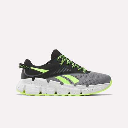 The Reebok Zig Dynamica 6 Running Shoes for big kids in Grey 4/Black/Digital Lime feature neon laces, black detailing, and a chunky speckled sole—engineered with Zig technology for superior running performance.