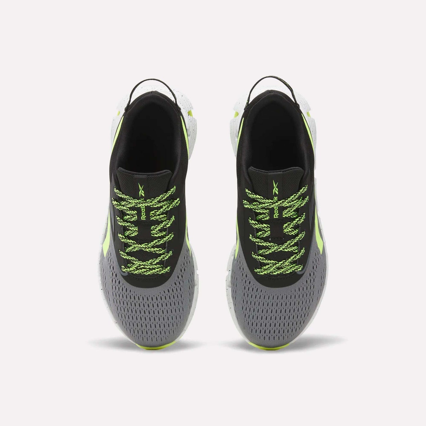 A pair of Reebok Zig Dynamica 6 Running Shoes for big kids, in gray with black interiors, neon green patterned laces, Zig technology soles, and light green accents, displayed from above on a plain white background.