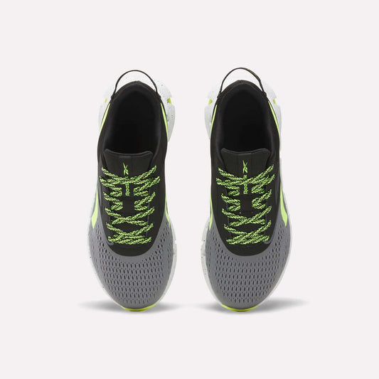 A pair of Reebok Zig Dynamica 6 Running Shoes for big kids, in gray with black interiors, neon green patterned laces, Zig technology soles, and light green accents, displayed from above on a plain white background.