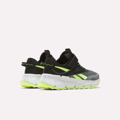 A pair of Reebok Zig Dynamica 6 Running Shoes for little kids in black and gray with neon yellow accents, Zig technology, white speckled soles, and chunky neon outsoles, shown on a plain white background.