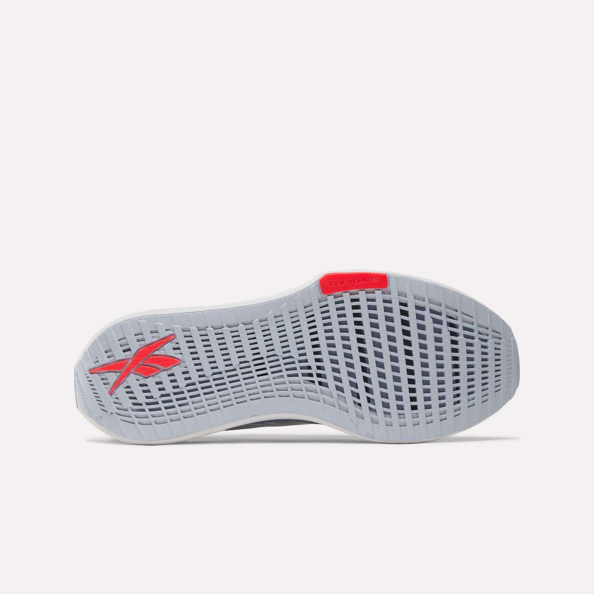 The image shows the sole of the Men's FloatZig Tread Running Shoes by Reebok in light gray, featuring a grid-like tread pattern, a red Reebok logo near the heel, and a red accent at the toe—perfect for treadmill workouts.