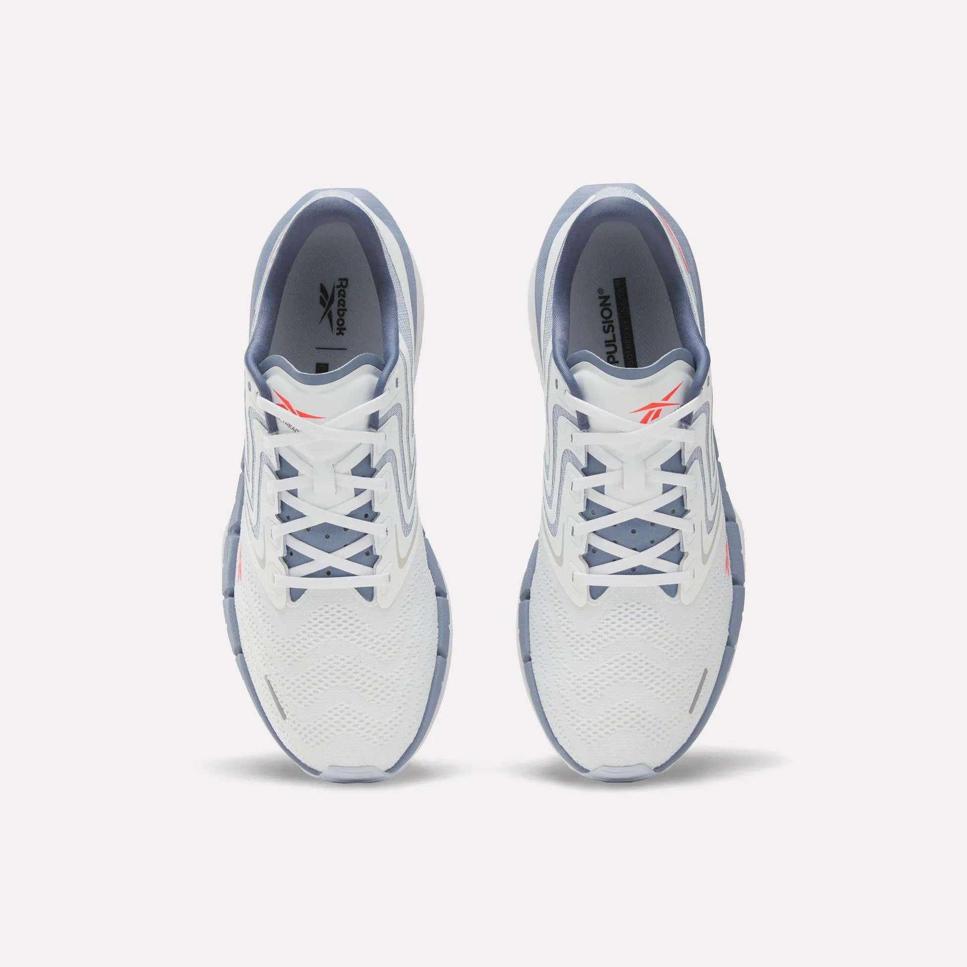 A pair of Reebok Men's FloatZig Tread Running Shoes in white with light blue accents viewed from above, highlighting the laces, mesh upper, and Reebok logo—perfect for treadmill workouts.