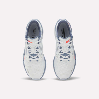 A pair of Reebok Men's FloatZig Tread Running Shoes in white with light blue accents viewed from above, highlighting the laces, mesh upper, and Reebok logo—perfect for treadmill workouts.
