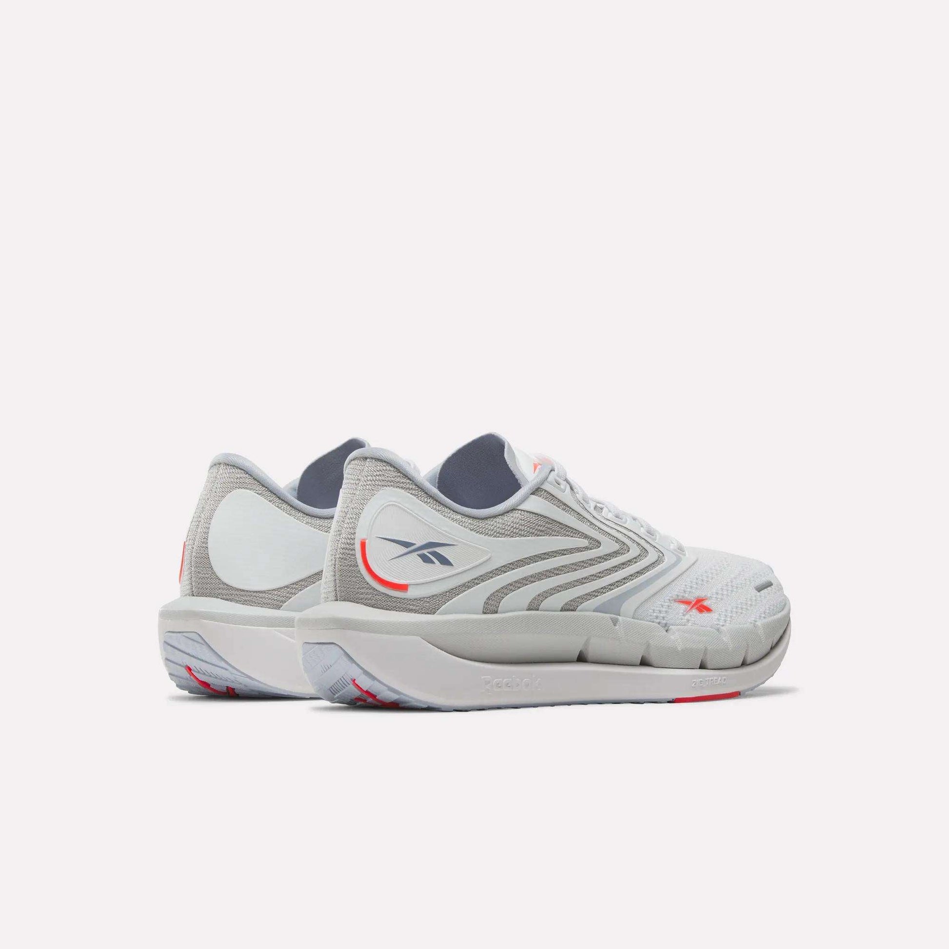 Reebok Women's FloatZig Tread Running Shoes in white and gray feature light gray soles, subtle red accents, and a breathable mesh upper—perfect for treadmill workouts—shown on a white background.