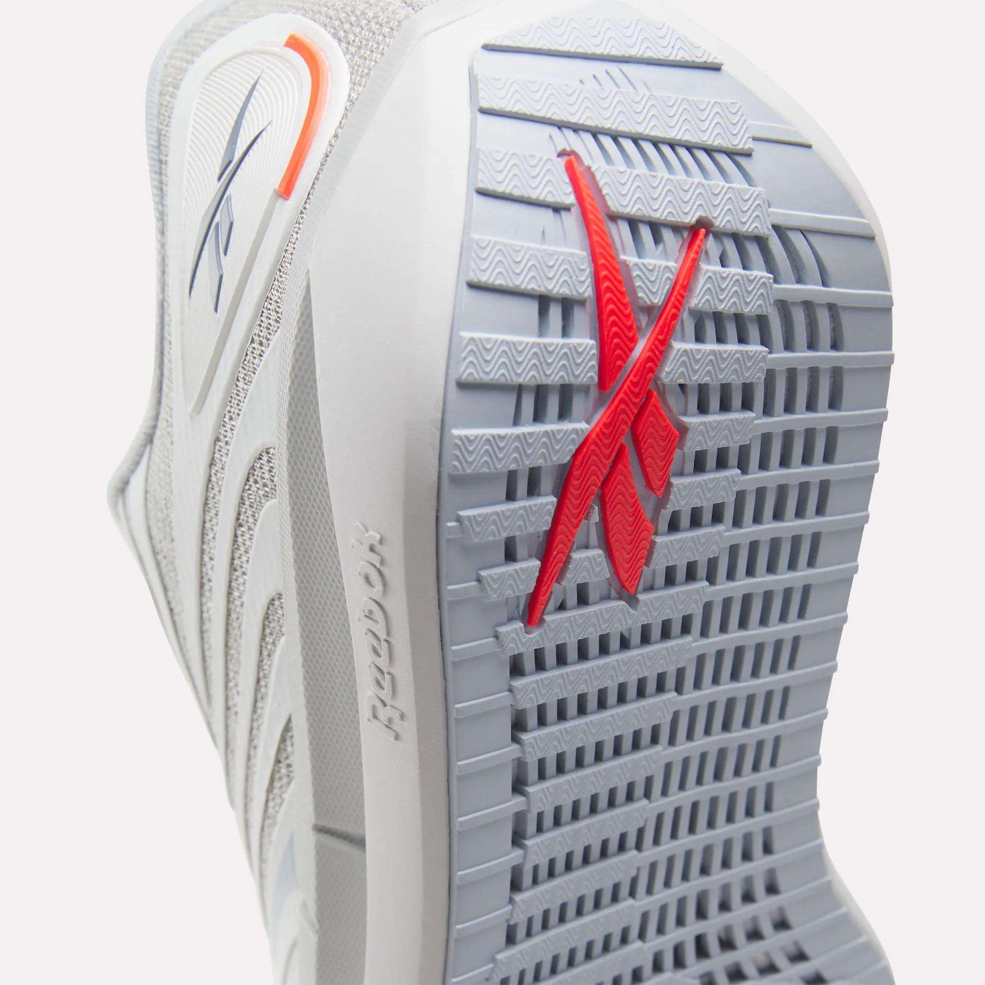Close-up of the sole of Reebok Women's FloatZig Tread Running Shoes in gray, showing a textured grip ideal for treadmill use and a red Reebok logo. Also visible: breathable mesh upper, side branding, and heel detail.