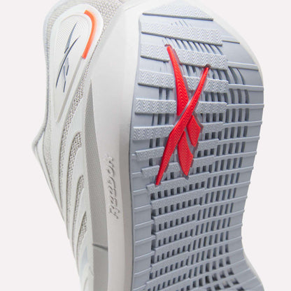 Close-up of the sole of Reebok Women's FloatZig Tread Running Shoes in gray, showing a textured grip ideal for treadmill use and a red Reebok logo. Also visible: breathable mesh upper, side branding, and heel detail.