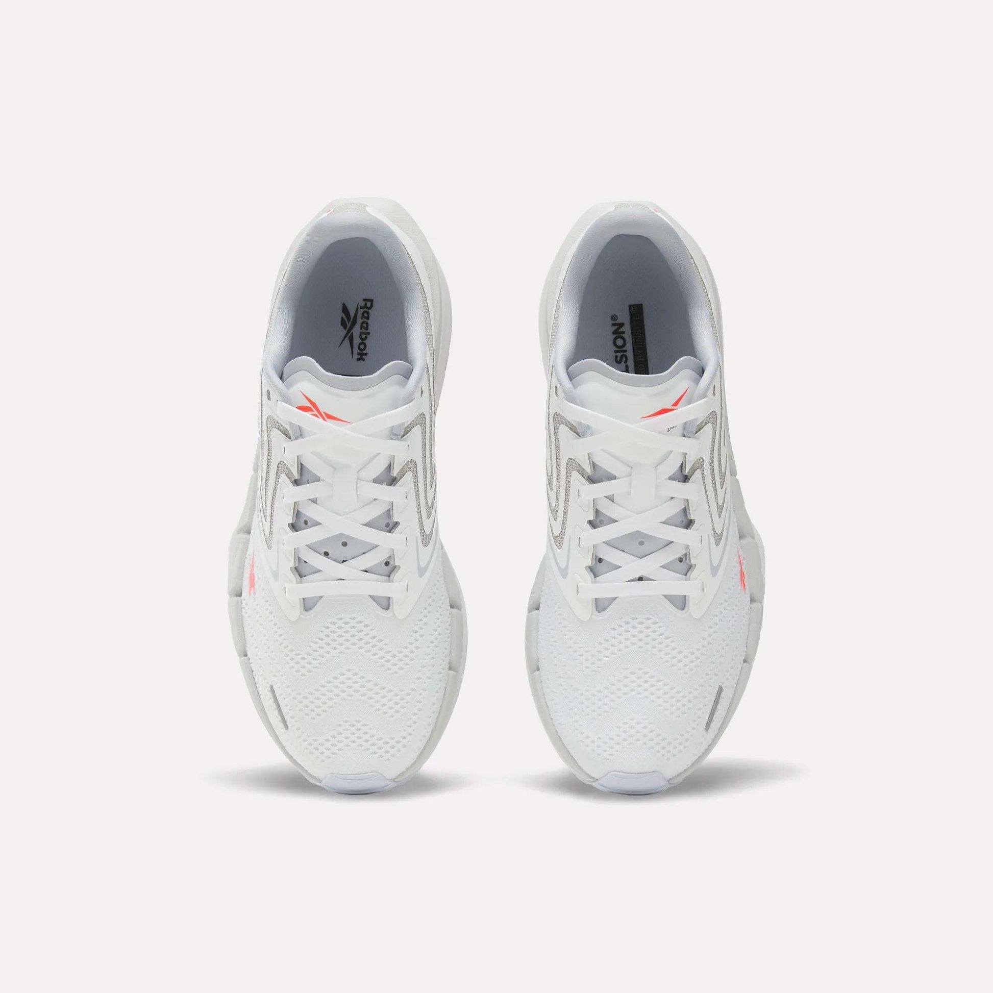 A pair of Women's FloatZig Tread Running Shoes by Reebok, viewed from above, with a breathable mesh upper, grey accents, and small orange Reebok logos on each tongue—perfect for treadmill workouts.
